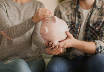 Two people hold a piggy bank and engage in communication about their military financial wellness