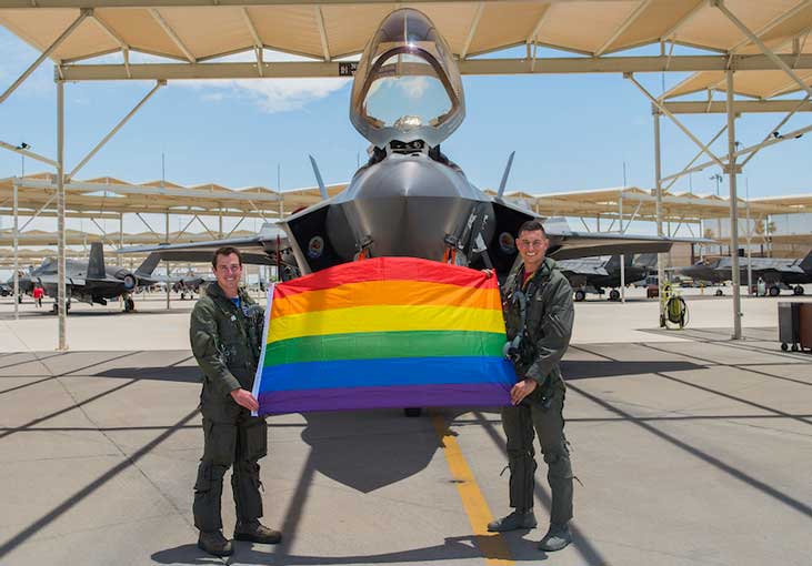 Airmen hold an LGBTQ+ Pride flag after a Pride Month flyby. (U.S. Air Force photo by Senior Airman Leala Marquez)