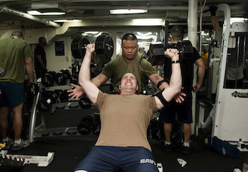 Sailors lifting weights together in gym to build strength and endurance for optimal military performance   U S  Navy photo by