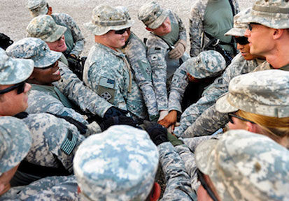 Group of soldiers in a circle putting their hands into the center highlighting teamwork for performance optimization and tota