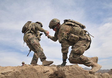 Soldier practices teamwork and pulls another soldier over wall during military training   U S  Army photo by Sgt  Kimberly Ha