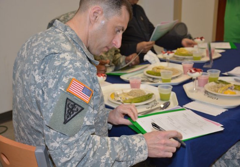 Military officer judges food competition at a dining facility showcasing healthy  flavorful food for peak performance nutriti