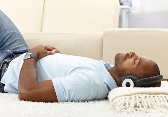 Man lying on floor wearing headphones practicing mediation for performance optimization and holistic health 