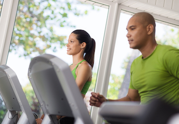 Man and woman running on treadmills follow Coast Guard health promotion programs for total force fitness and wellness 