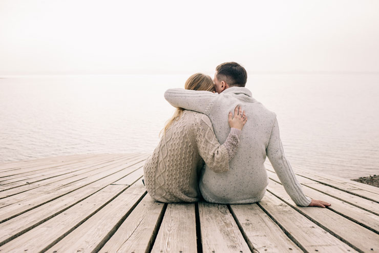 Couple sitting on a dock hugging each other