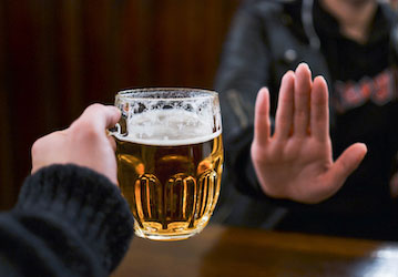 Person saying no to beer in order to promote military wellness and performance 