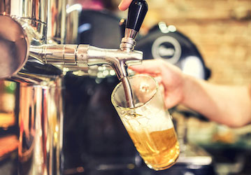 Hand pouring a draft beer from tap emphasizes moderate alcohol consumption for optimal health and wellness  