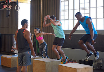 Group of people in a gym doing box jumps demonstrating military fitness  performance optimization  and total force fitness 