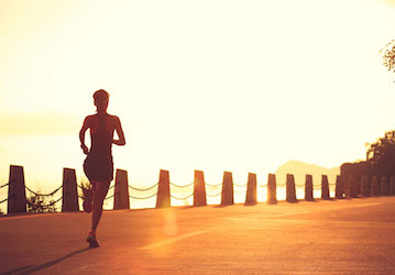 Woman running on a paved path at sunrise training for military performance optimization  