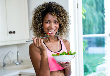 Woman in workout clothes practicing performance nutrition strategy by fueling with a healthy salad 