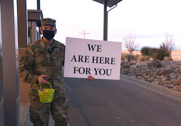 Chaplain holding sign saying "We are here for you" Sailor in uniform holding a sign with words "We Are Here For You" emphasizing holistic wellness through spiritual fitness. 