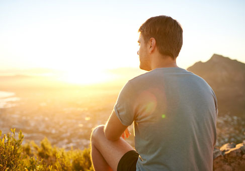 Man mindfully watching a sunrise to help increase mental health and resilience 