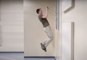 Person doing a pull up improves physical fitness and strengthens foundational movements for optimal military performance  