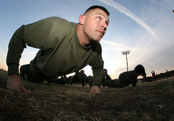 Marine leads his team in performing squad push-ups during a combat fitness circuit course to improve military fitness