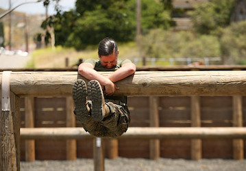Uniformed Marine hanging on a log during a military workout enhances muscular endurance and mental health resilience (U.S. Marine Photo by Sgt Tayler P. Schwamb)