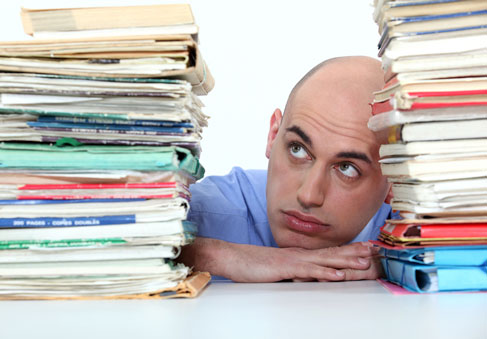 Man procrastinating on large stack of work and in need of HPRC resources for performance psychology 