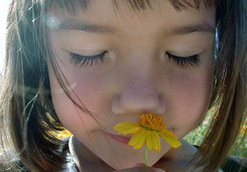 Girl smelling flower finds awe in nature and experiences positive feelings and holistic wellness  