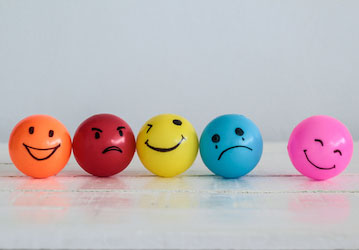 Different color balls have faces drawn on them indicating different emotions that impact relationships  resilience  and milit