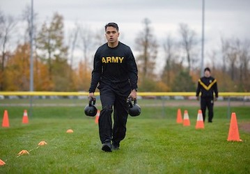 Army solider carries kettlebells during training for a military workout to achieve military fitness and performance optimizat
