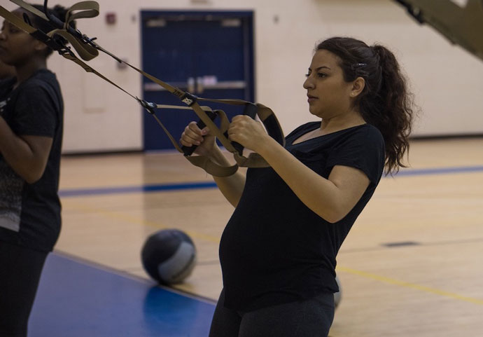 Senior Airman performs TRX exercises in order to maintain military fitness during pregnancy.