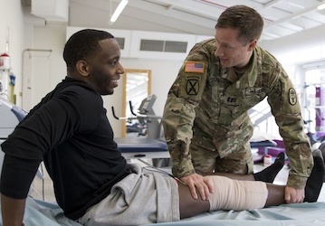 Uniformed military member helps man with injury prevention to improve his performance optimization  Photo by Marcy Sanchez