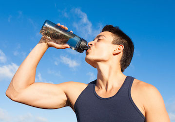 Man drinks water from water bottle to fuel his body after military workout using performance nutrition strategies 