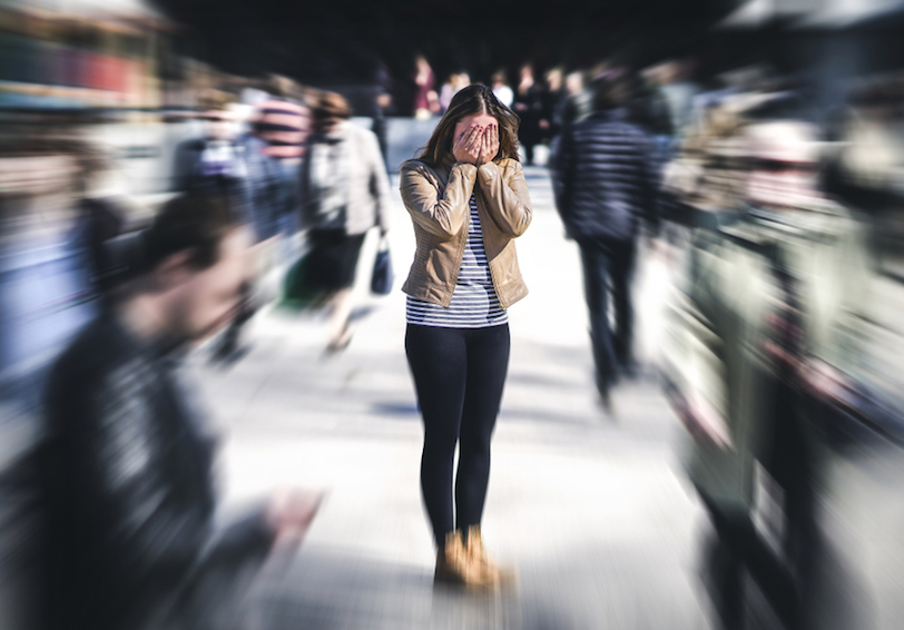 Overwhelmed woman standing in the center of a blurry crowd needs HPRC mental health resources for managing PTSD  