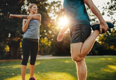 Man and woman stretching before exercise to optimize physical performance and prevent injury 