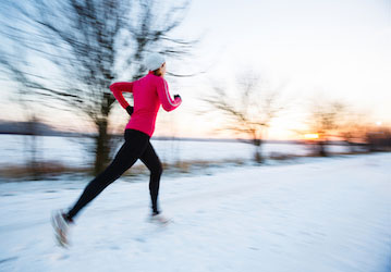 Person running outside on snowy day boosts physical health and performance by staying on track with fitness goals  