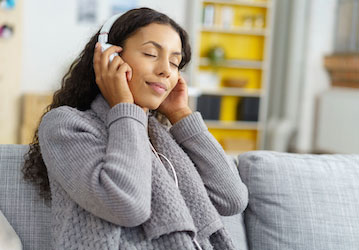 Woman listens to headphones with eyes closed and performs autogenic training for improved focus and stress management  