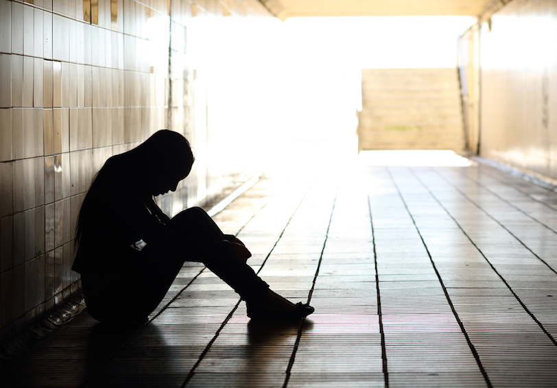 Person sits alone in dim hallway in need of military wellness and mental health information
