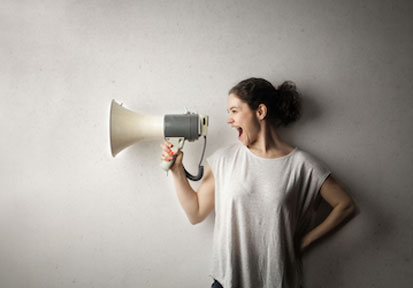 Woman yelling into a megaphone emphasizes assertive communication for building healthy relationships  
