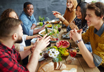 Friends at a table conversing during shared mealtime highlight the benefit of social connection for total force fitness 