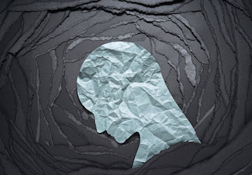 Profile silhouette in a spiral of black paper illustrates anxiety s toll on mental health and military wellness  