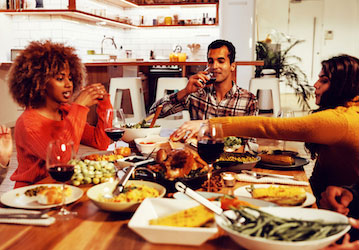 Friends dining together use HPRC resilience tips for fueling performance nutrition during a holiday gathering 