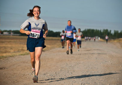 Smiling woman runs during the Air Force Marathon with increased resiliency due to the positive impact of physical fitness on 