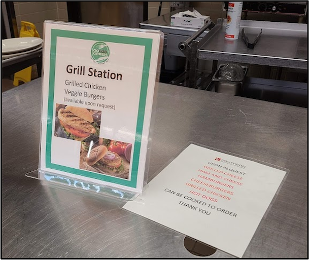 Clear, close up photo of grill station with green-coded foods