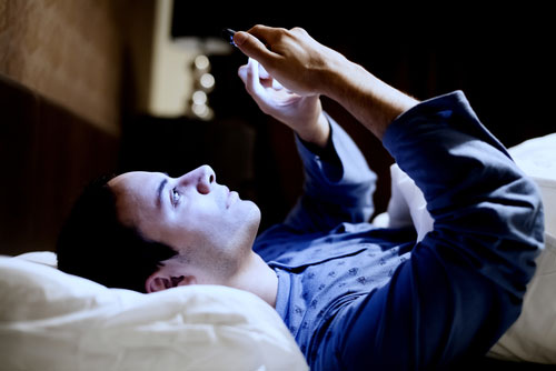 Man with mobile phone in bed