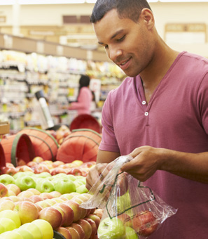 Man picking apples at grocery store chooses healthy food that fuels performance nutrition and fitness training.