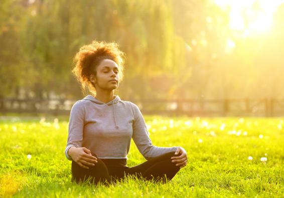 Woman meditating in a park for performance optimization and holistic health 