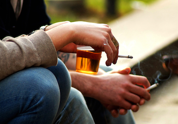 Two military members sit holding cigarettes and beer in need of healthy performance optimization information 