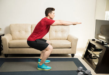 Man working out in living room improves physical fitness with strength training  