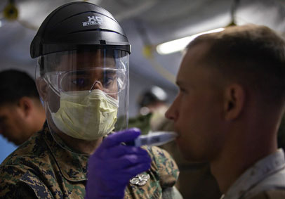 Service Member wears a face shield  gloves  and takes a military member s temperature to maintain military wellness during CO