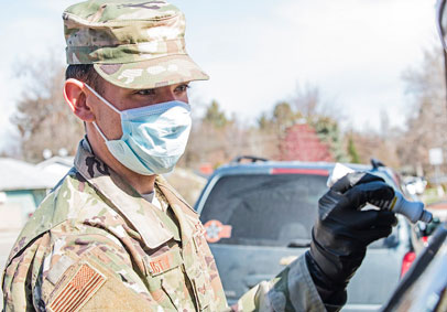 Service Members with a mask and gloves takes someone s temperature during coronavirus response in an effort to maintain milit