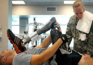 Soldier holding his prosthetic leg and being examined by doctor as part of a military and VHA goal to improve pain management