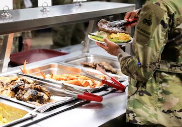 A culinary specialist adds a steak to a Soldier   s plate  Photo By Spc  Matthew Marcellus