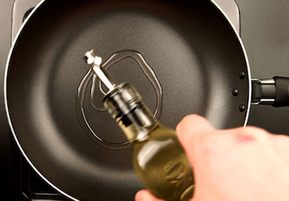 Olive oil being drizzled onto a pan shows the nutritional benefit of healthy fats for military fitness and wellness  