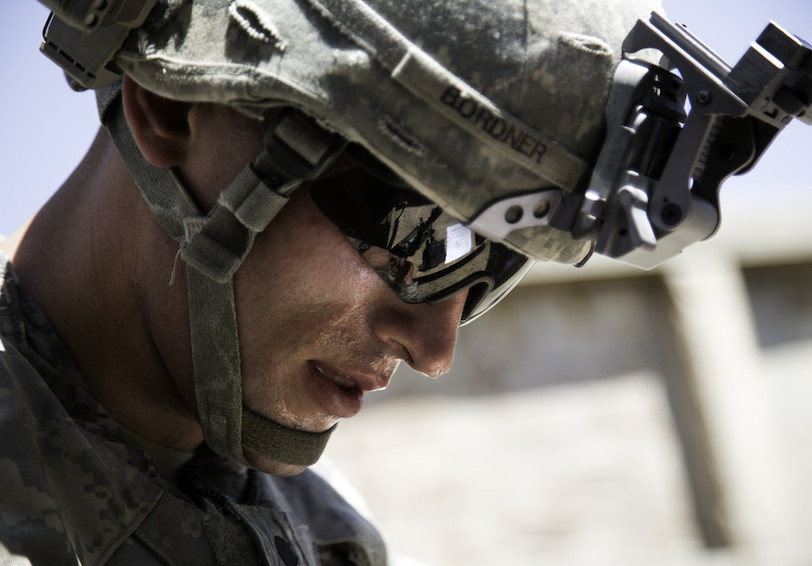 Service Member wearing military helmet and equipment looks hot outdoors after a military fitness exercise