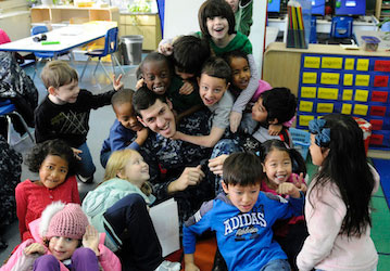 Group of children playing with a service member in a classroom as part of initiative to increase family readiness and total f