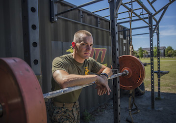 Marine resting on barbell after difficult workout to improve total force fitness and military performance  Photo By  Cpl  Ash